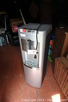 Full view of silver Whirlpool water dispenser with cord and labels visible.