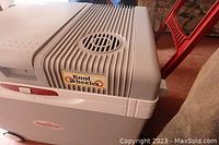 Top and side view of Koolatron Koolwheeler electric cooler showing vented top and latch handle with Kool Wheeler and Koolatron branding.