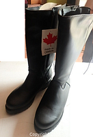 Front view of the tall black boots showing smooth texture, rounded toe, and made in Canada label.