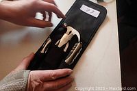 Open black fabric case showing mini hammer, folding knife and multi-tool securely held by elastic loops