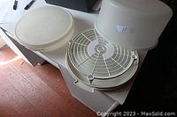 Tupperware cake carrier base, white wire shelf and translucent white dome cover shown on a table.