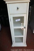 Front view showing drawer on top and glass door cupboard below with three shelves inside.