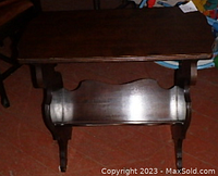 Front view of the wooden magazine rack table showing the top surface and magazine storage shelf underneath with curved side panels.