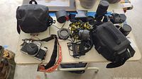 Overview of all equipment on table including cameras, lenses, bags, lights, and accessories