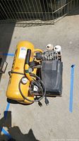 Full overhead photo showing the yellow twin stack DeWalt compressor with its circular pressure gauge and electric cord coiled on top