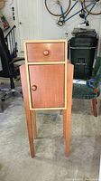 Photo of Ethan Allen wooden cabinet stand showing front with drawer and door, tall legs, and the two-tone wood finish.