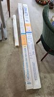 Two long white cardboard boxes and one rolled tube showing overall lot contents