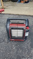 Front view of Mr Heater Big Buddy propane heater showing metal protective grate, red base, and black handle.
