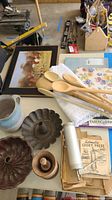 Photo showing cookie press, two bundt pans, wooden mortar and pestle, wooden spoons, pitcher, and linens