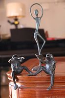 Photo of two pewter frog statues sitting on a wooden surface, one playing violin, one reading sheet music, showing their detailed craftsmanship and posture.