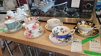 Front view of six assorted teacup and saucer sets on wooden surface