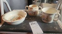 Shows three piece set including shallow dish, handled bowl, and handled cup with Bunnykins print