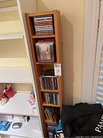 Front view of tall narrow Ikea wood-tone shelf with CDs on five shelves