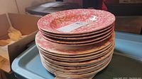 Stack of six pink floral patterned bowls with a fruit and vine motif on the rim.