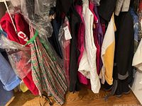 Photo showing multiple women's jackets and sportswear hanging on a rack with various colors and styles including a red jacket and plaid top.