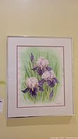 Full view of framed watercolour painting showing three irises with green leaves in the background.