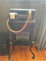 Full view of Dictaphone Model 12 on metal stand with microphone hose and coiled cable