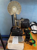 Overview of press camera body, handheld flash attachment on left and assorted cables