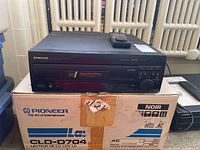 Front view of black Pioneer CLD-D704 player on original box with remote on top