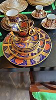 Stacked Caverswall Blue Cobalt Imperial cup and saucer with striking cobalt blue, orange-red flower motifs, and gold accents alongside other china sets.