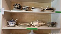 Top shelf with Royal Winton Peking Black soup bowls, saucers, cake plate; Royal Ducal tureen, bowl, gravy boat; two Asian bowls.