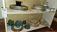 Shelf with stacked plates, cups and saucers in various patterns