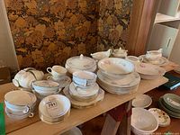 Overview of the assorted Homer Laughlin Tulip Eggshell Georgian china pieces on a wooden surface showing multiple types of plates, bowls, and serving pieces with floral decoration.