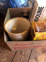 Box with ceramic bowl, mandoline slicer box, plastic container, and other utensils visible
