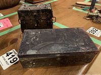 Front view of rectangular embossed metal box and small trunk side by side