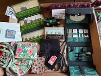 Full lot overview showing sewing needles, scissors, thread winders, fabric scraps, miniature model truck and tape measure.