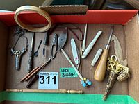 Top-down view of entire assortment of antique sewing and needlework tools arranged in cardboard box