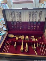 Open wooden case showing eight Birks dinner knives secured in lid slots