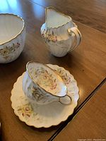 Close-up of creamer, sugar bowl and cup showing floral and gold trim details