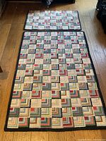 Photo showing the two rugs laid out on a hardwood floor, displaying their full geometric patterned design with multiple colored squares and a black border.
