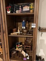 Shelf with miniature furniture, wood sculptures, and collectible miniature books.
