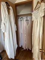 Three vintage nightgowns hanging on door and closet rod in wood interior room