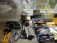 Table with yellow rotary cutters, black-and-green carrying case, Gingher sharpening stone, and clear pouches with sewing supplies