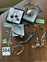 Overview of sterling silver jewelry pieces on wooden surface including necklaces, bracelets, charms, and a small silver object.