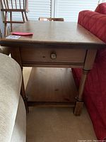 Angled front view of side table showing drawer, top surface, turned legs and lower shelf