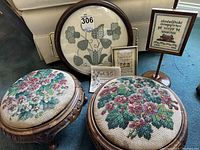 Two round foot stools with carved walnut frames and floral beadwork tops, tray and samplers in background