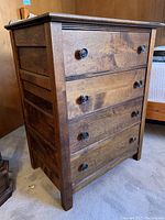 Front three-quarter view showing all four drawers and round black metal knobs