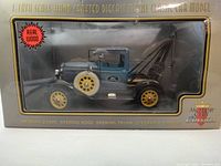 Front view of 1:18 scale blue diecast 1931 Ford Model A Tow Truck in original box, showing the model in clear display window with yellow wheels and black tow boom assembly.