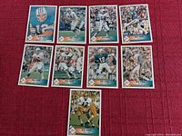 Photo of nine Bob Griese football cards laid out on a red surface showing various action shots from the 1992 Pacific set.