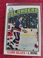 Close-up photo of Clark Gillies hockey card in protective plastic sleeve showing player in New York Islanders jersey during game action.
