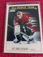 Photo of a single Score All Rookie Team Ed Belfour hockey card in protective sleeve showing Ed Belfour in goalie pose wearing red Chicago Blackhawks uniform.