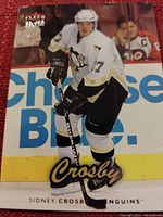 Close-up image of Fleer Ultra hockey card featuring Sidney Crosby in Pittsburgh Penguins jersey during game.