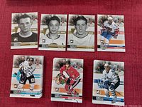 Photo of seven hockey cards spread out showing a mix of black and white rookie portraits and color action shots.