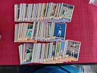 Photo showing multiple stacks of Nolan Ryan baseball cards arranged on a red surface, with various action and portrait shots.