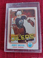 Photo of vintage O-Pee-Chee hockey card of Andy Moog in goalie gear for Edmonton Oilers in protective plastic sleeve.