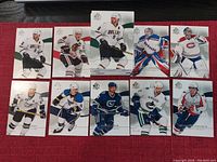 Photo showing 10 SP Authentic hockey cards featuring various players from different NHL teams, arranged neatly on a red surface.